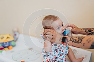 Tattooed mom playing with her baby in a hospital office.