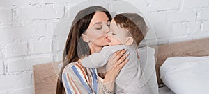 tattooed mother kissing baby boy in