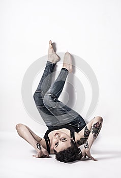 Tattooed natual looking woman with short black hair lying down on bright background