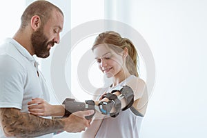 Tattooed physiotherapist who puts an orthosis on the hand of a young patient