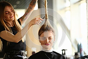 Tattooed Stylist Cutting Hair of Closed Eyes Woman