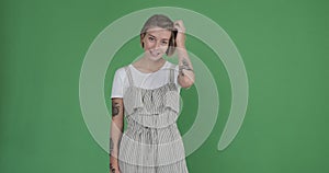 Tattooed woman in frill dungarees over green background