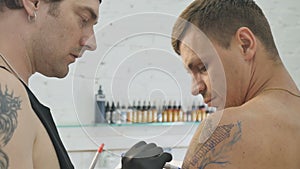 The tattooer draws a finishing lines of sketch on the skin before tattooing