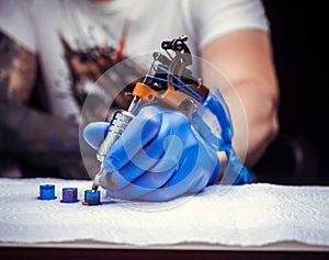 A tattooer, holding in his hand, a tattoo gun.