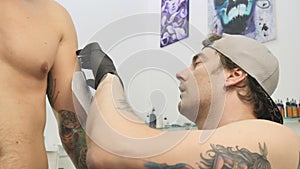 The tattooist applies the sketch on the man`s arm