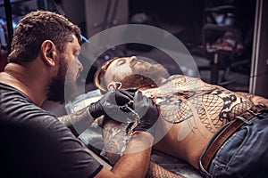 Tattooist makes a tattoo on the client& x27;s tattoo studio