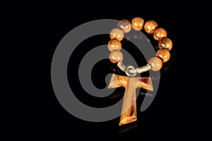 Tau - Wooden Cross and Rosary Bead on black background