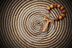 Tau - Wooden Cross and Rosary Bead on woven wicker texture