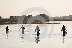 Taungthaman Lake, Amarapura in Myanmar. Fishermen into the water at sunset