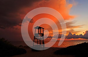 Tawny cloudy sunset silhouetting life guard post watch tower