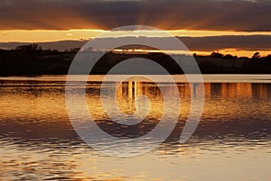 Tawny sunset reflected across a shimmering Ravensthorpe Reservoir, Ravensthorpe, Northamptonshire