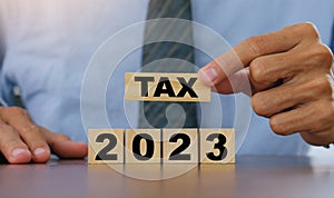 TAX in 2023 concept,Business man holding wooden block. State taxes,tax payment, governant ,finance, tax accounting, statistics and