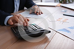 Tax accountant with calculator working at table in office, closeup