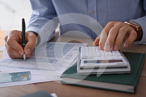 Tax accountant with calculator working at table in office, closeup