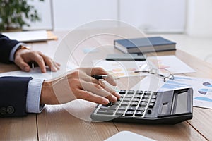 Tax accountant with calculator working at table in office, closeup