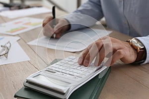 Tax accountant with calculator working at wooden table, closeup
