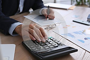 Tax accountant with calculator working at wooden table, closeup