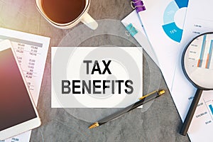 TAX BENEFITS is written in a document on the office desk, coffee, diagram and smartfon