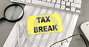 TAX BREAK text written on a sticky on chart with keyboard and magnifier