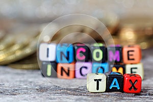 Tax concept with TAX word on alphabet block with stacked coin in the background