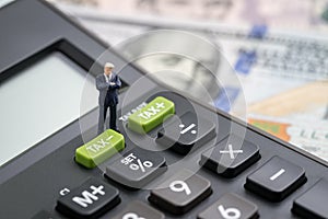 Tax cuts or reduce concept, miniature people business man president standing with TAX minus button on calculator with background