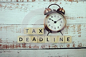 Tax Deadline with alarm clock with space copy on wooden background photo