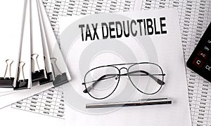 TAX DEDUCTIBLE text on paper with chart and office tools , business concept
