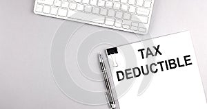 TAX DEDUCTIBLE text on paper with keyboard on grey background