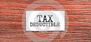 TAX DEDUCTIBLE text on the piece of paper on the red wood background