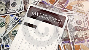 TAX DEDUCTION text on display calculator on the dollars background