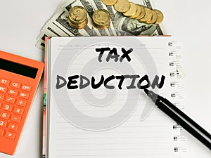 Tax Deduction written on note book with calculator,pen and money.