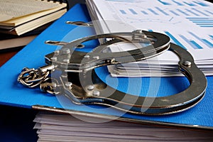 Tax evasion. Handcuffs and pile of financial papers photo