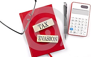 TAX EVASION text on wooden block on red notebook
