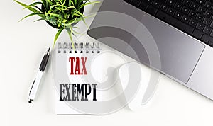 TAX EXEMPT text written on notebook with laptop and mouse , white background photo