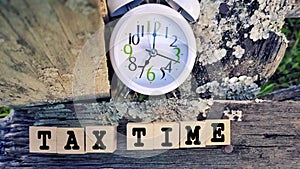 Tax-filling concept - Tax time words on wooden blocks with clock background