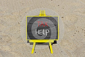 Tax help symbol. Concept words Tax help on wooden blocks on a beautiful black chalk blackboard on a beautiful beach sand