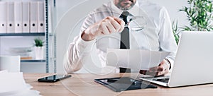 Tax inspector and financial auditor looking through magnifying glass, inspecting financial papers