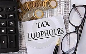 TAX LOOPHOLES - words on a white piece of paper on the background of a calculator, pennies and glasses