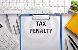 TAX PENALTY written on the paper with keyboard, chart, calculator and notebook