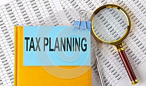 TAX PLANNING text on sticker on notebook with magnifier and chart. Business concept