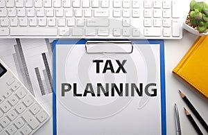 TAX PLANNING written on paper with keyboard, chart, calculator and notebook