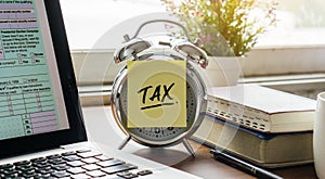 Tax post-it on alarm clock with U.S IRS 1040 form on laptop.Pay tax or vat in 2022 years. Business and tax concept