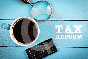 Tax Reform. Coffee mug, magnifying glass and calculator on a wooden background