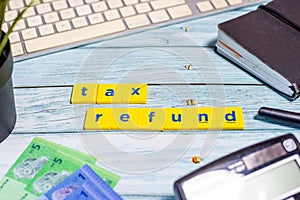 Tax Refund Concept - Calculator, keyboard, Ringgit Malaysia on blue wooden background