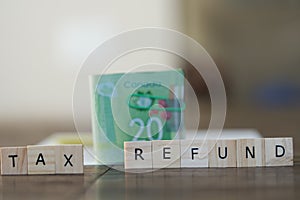 Tax refund spelled out in letters with Canadian Dollar cash in background