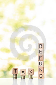 Tax refund word written on wood cubes, stacks of coins