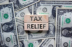 Tax relief symbol. Concept words `tax relief` on wooden blocks on a beautiful background from dollar bills. Business and tax photo