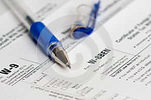 Tax reporting forms with opened blue pen