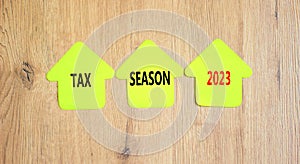 Tax season 2023 symbol. Concept words Tax season 2023 on green paper houses on a beautiful wooden table wooden background.