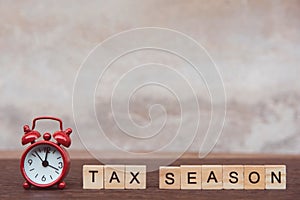 Tax season with wooden alphabet blocks and Red alarm clock, on Table dark plank wooden background with copy space